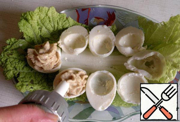 For the beauty of the dish, the resulting paste is placed in a pastry syringe or cornet. Squeeze the paste in half of the eggs. Decorate the dish with lettuce leaves, crumbled yolk, dill and tomatoes.