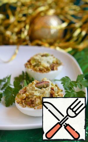 It remains only to stuff the cheese mass halves of eggs, sprinkle with pistachio crumbs on top, decorate with herbs and serve.