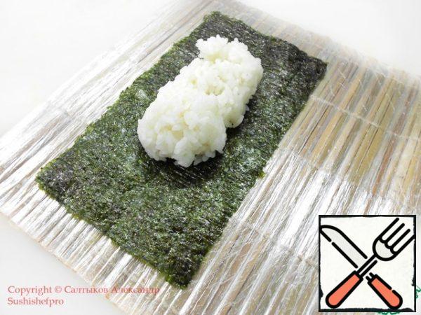On the mat Makisu place half a sheet of seaweed "nori". Next, moisten your hands with water, in the center of the sheet put the required amount of finished rice for rolls.