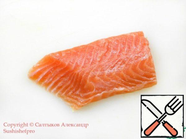 Place a piece of lightly salted salmon on a cutting board.
