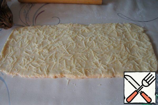 Roll out the dough on a table sprinkled with flour into a rectangular layer of the same width as the sticks you plan to make. The thickness of the formation should be about 3-4 mm.

