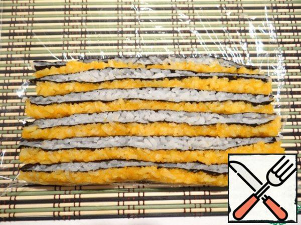 I lay out strips, having turned them so that white and orange layers of rice, on the bamboo mat covered with a film were visible.