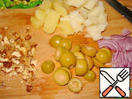 Cut the potatoes, chop the nuts. Cut the olives into slices. Herring-pieces. Chop the onions.
