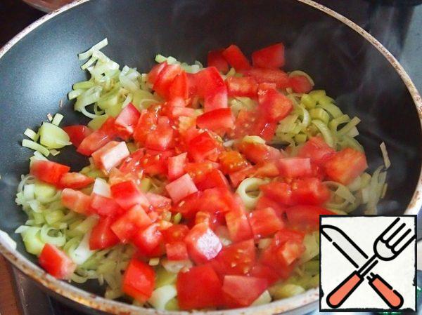 While the dough is baked, cut the leek into rings, remove the pulp from the tomato and cut it into pieces, grind garlic in a mortar or finely cut. Fry in a pan with a spoon of vegetable oil for 5 minutes.