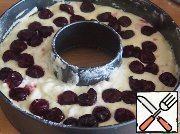 In a form greased with oil and sprinkled with flour, put half of the dough, sprinkle with cherries.
If you use frozen cherries, it needs to be thawed.
