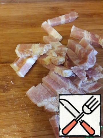 It is good to use a deep frying pan or a saucepan to prepare a dish.
Cut the ham into cubes. Instead of a ham it is possible to take bacon or boiled-smoked brisket