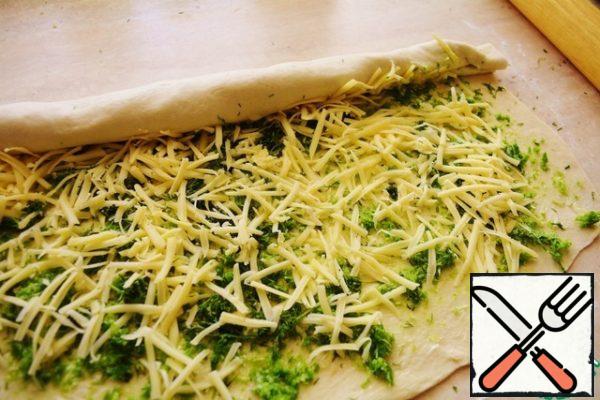 Sprinkle with grated cheese, and roll into a roll as tightly as possible, tighter.