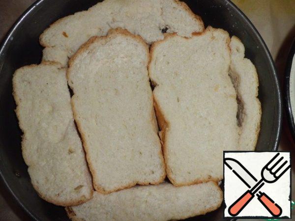 Bread cut into pieces about 3 cm in thickness, not less. Dip in milk on both sides, squeeze a little and spread them the bottom of the form.