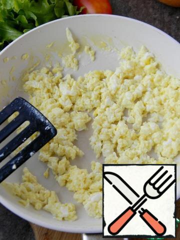 And quickly stir with a spatula, breaking lumps. The eggs are ready remove from the heat.