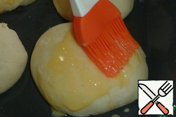 Brush the buns with beaten egg yolk.

