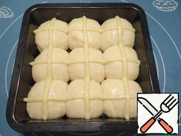Brush the dough with beaten egg. Transfer the sauce to a syringe or a pastry bag with a nozzle with a round hole, draw a mesh on the dough balls.
