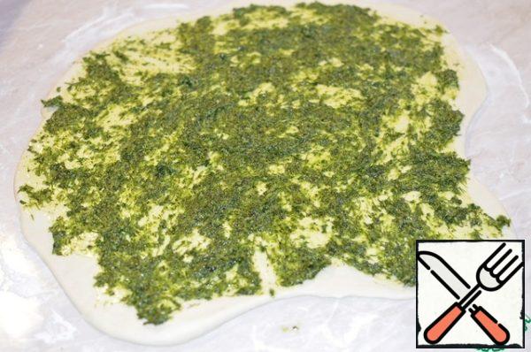The finished dough is rolled into an oval, spread the greens on its surface. leave a little green mass to coat the finished bread, so it will be even more fragrant.