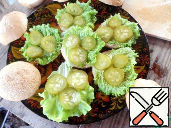 Hamburger buns cut in half, the lower part to grease with mayonnaise, put the leaves of lettuce and slices of pickles.