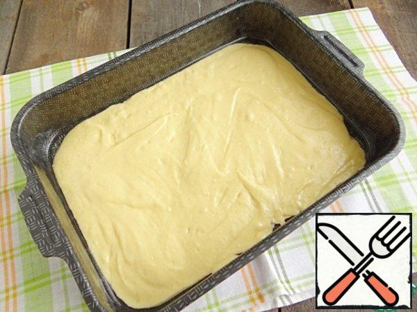To bake this cake, I use a rectangular shape measuring 23*30 cm. Grease the mold with vegetable oil. Pour half of the dough into the mold, spread the dough on the bottom with a spoon.
