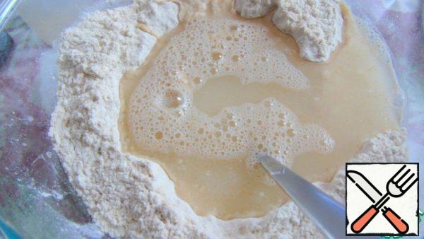 Make a recess in the middle and pour in honey and water.
