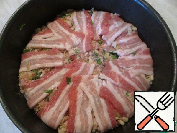 Evenly fill the form with minced meat and cover with strips of bacon.