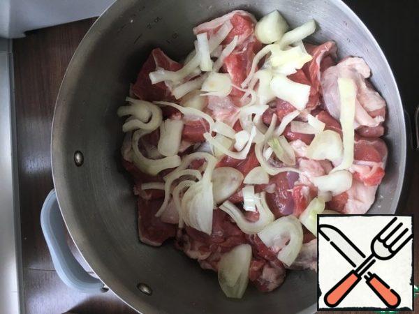 Onions should be cut into half rings. Put the onion on a layer of lamb.