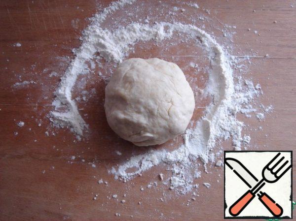 The dough is well kneaded and rolled into a ball on a floured surface.