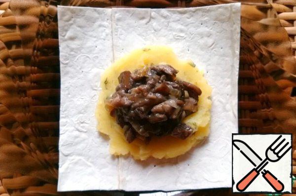 On each square spread on a tablespoon of mashed potatoes with herbs and mushrooms with onions, a little level, pressing, and then turn into an envelope.