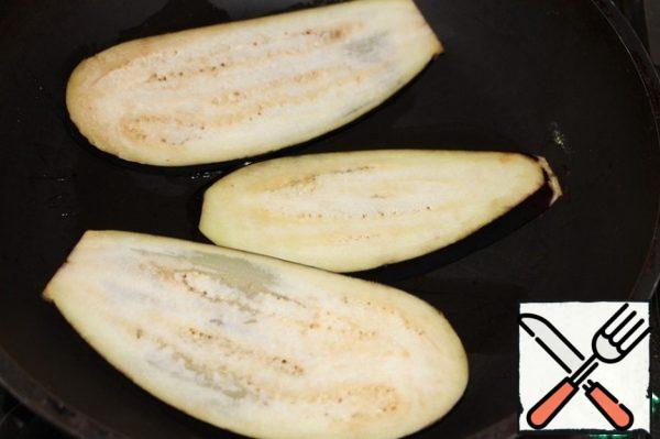 Slices of eggplant fry in vegetable oil, then put on a paper towel to absorb excess oil.