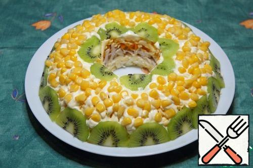Decorate the salad with thin slices of kiwi and corn.