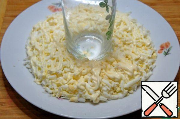 On a flat plate to put a serving ring or glass. Around the ring put the eggs on top, apply a mesh of mayonnaise.