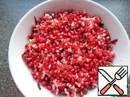 Complete the design of the salad-spread the pomegranate seeds.