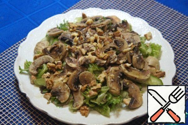Place on a flat plate with a small slide. Put the pickled mushrooms on top, sprinkle with nuts and pour over the remaining dressing.