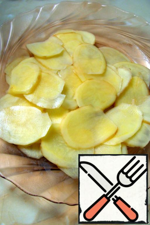 Wash the potatoes with a brush, and peel or not, decide for yourself.
Cut into circles or slices as thin as possible - it is most convenient to do it with a slicer or a special grater with a holder for the product, which cooks call "mandolin". (I had a regular peeler.)