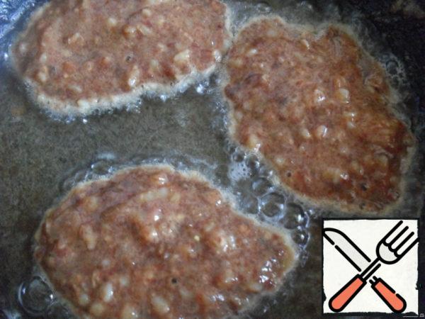 Minced spread with a tablespoon in a frying pan with hot oil.