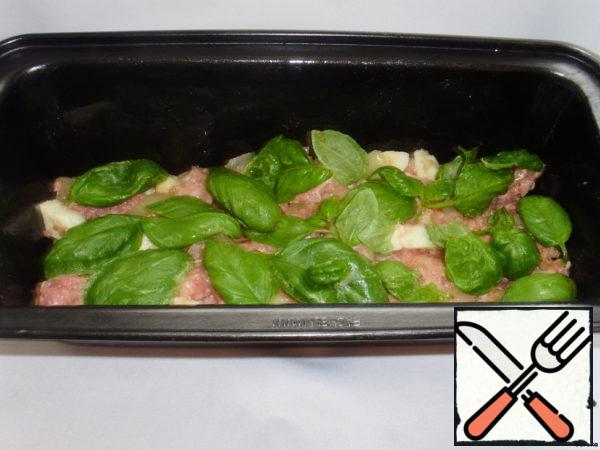 Grease the cupcake mold with butter. Lay out the filling in layers and sprinkle with basil leaves.
