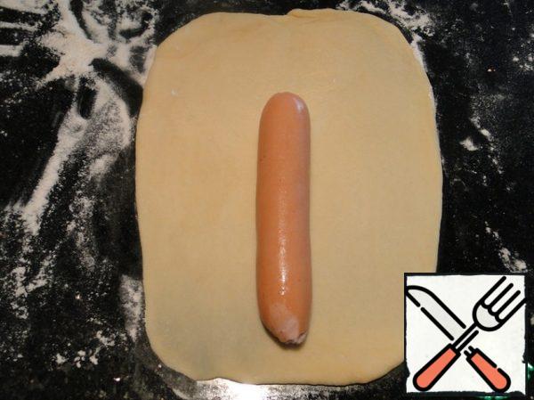 From large pieces of roll out the rectangles and put in the middle of the sausage, closer to the bottom edge.