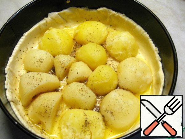 Halves of potatoes spread out on the dough slices down, salt and pepper.