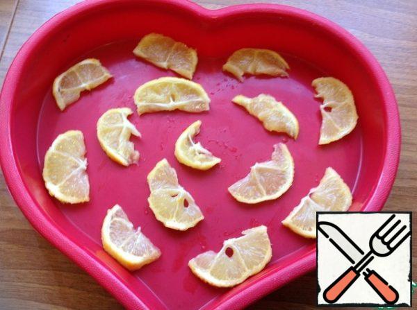 With lemon with which removed the zest, cut into half rings, remove seeds and put on the bottom of the form.
