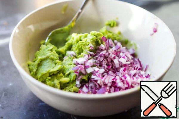 Prepare the guacamole. Peel the avocado and grind its pulp into a puree. You can do it with a fork, if the fruit is very ripe or with a blender. I love when in guacamole felt small pieces, so not much grind. Cut the red onion very finely and mix with avocado puree.