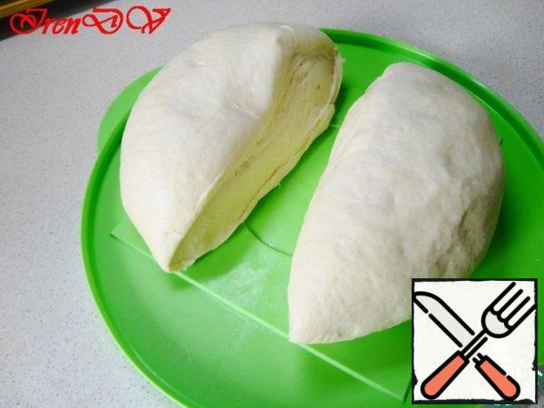 The dough is spread on a table, emminem, cut into two parts. Such oval blanks are obtained.