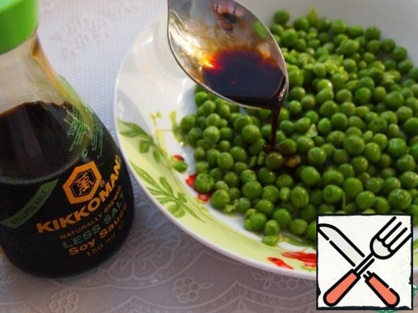 Rinse green peas (frozen) under cold water, pour soy sauce, mix, leave for 30 minutes to soak.
