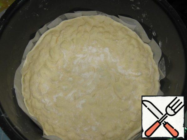 In the bowl of slow cooker put baking paper and distribute the dough across the surface, making the bumpers.