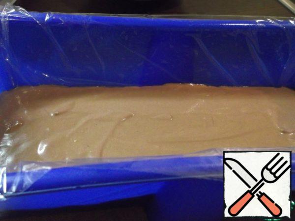 Carefully distribute the first chocolate layer into the mold - dark chocolate. Align it.
