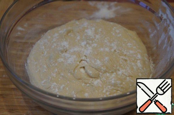 Dipping your hands in flour, roll the dough into a ball (not too well, but somehow), put it in a bowl, tighten with a film and leave at room temperature until the dough increases in volume by 2 times.
