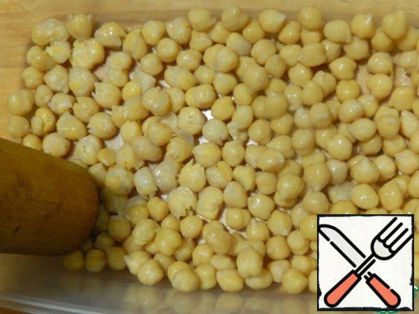 Ready chickpeas throw in a colander, collect the liquid and use it to make soup. Put the chickpeas in a bowl and slightly flatten a portion of the peas with a potato masher.