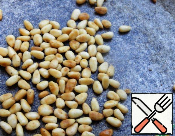 Meanwhile, take pine nuts and fry them in a dry frying pan until a pleasant aroma appears.
