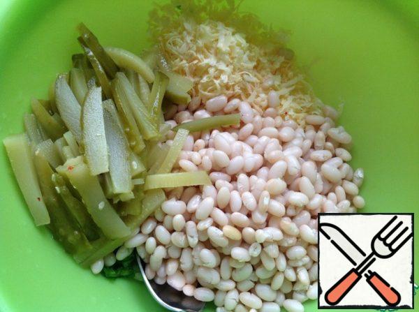 Add the boiled beans. Grate the cheese on a medium grater, cut the cucumbers into strips.
