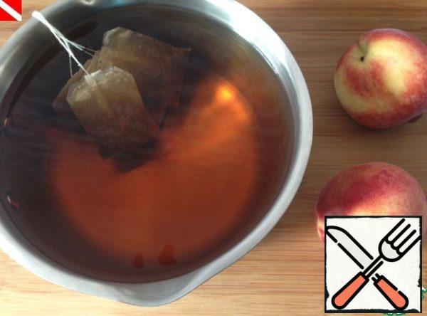 Boil 6 cups of water, put the tea bags in hot water. Let it brew to the desired color and taste. Take out the tea bags and let the tea cool down. Before serving, mix the tea and peach syrup, add the leaves and berries of black currant.
