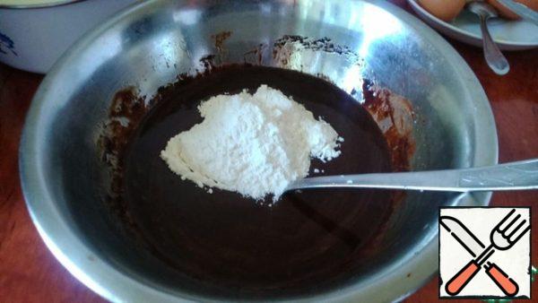 Add flour and baking powder to our chocolate mixture.
Thoroughly knead everything (the dough should be quite liquid).