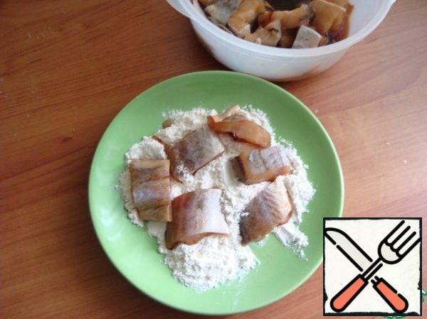 Roll the pickled pieces of fish in flour.
