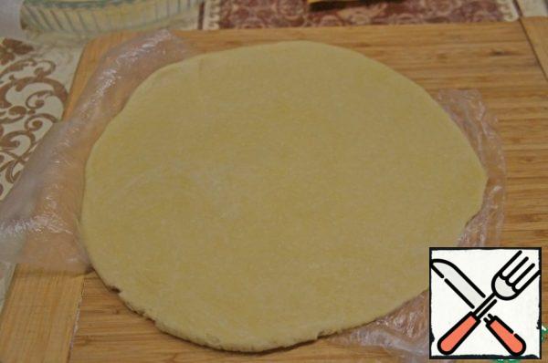 Roll the dough into a round layer with a diameter slightly larger than the shape.