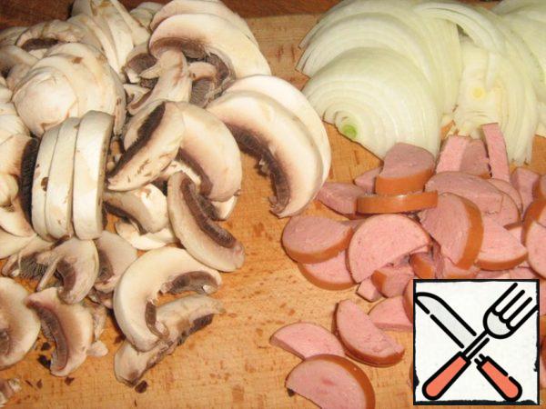 Cut the mushrooms into plates (chop the legs).
Cut the onion into thin half rings.
Sausages are also half-rings.