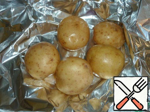 Wash potatoes with a brush, wrap in foil and bake in the oven until ready, it will take about an hour.