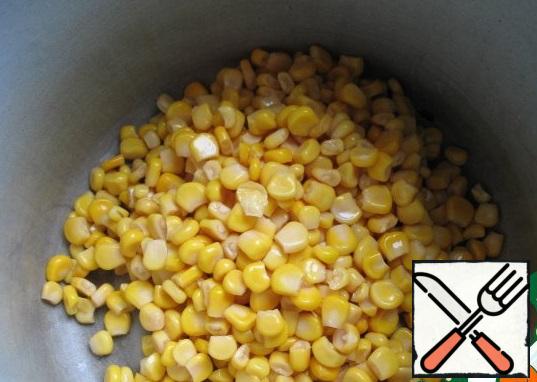 Open a can of canned corn, drain and pour corn.